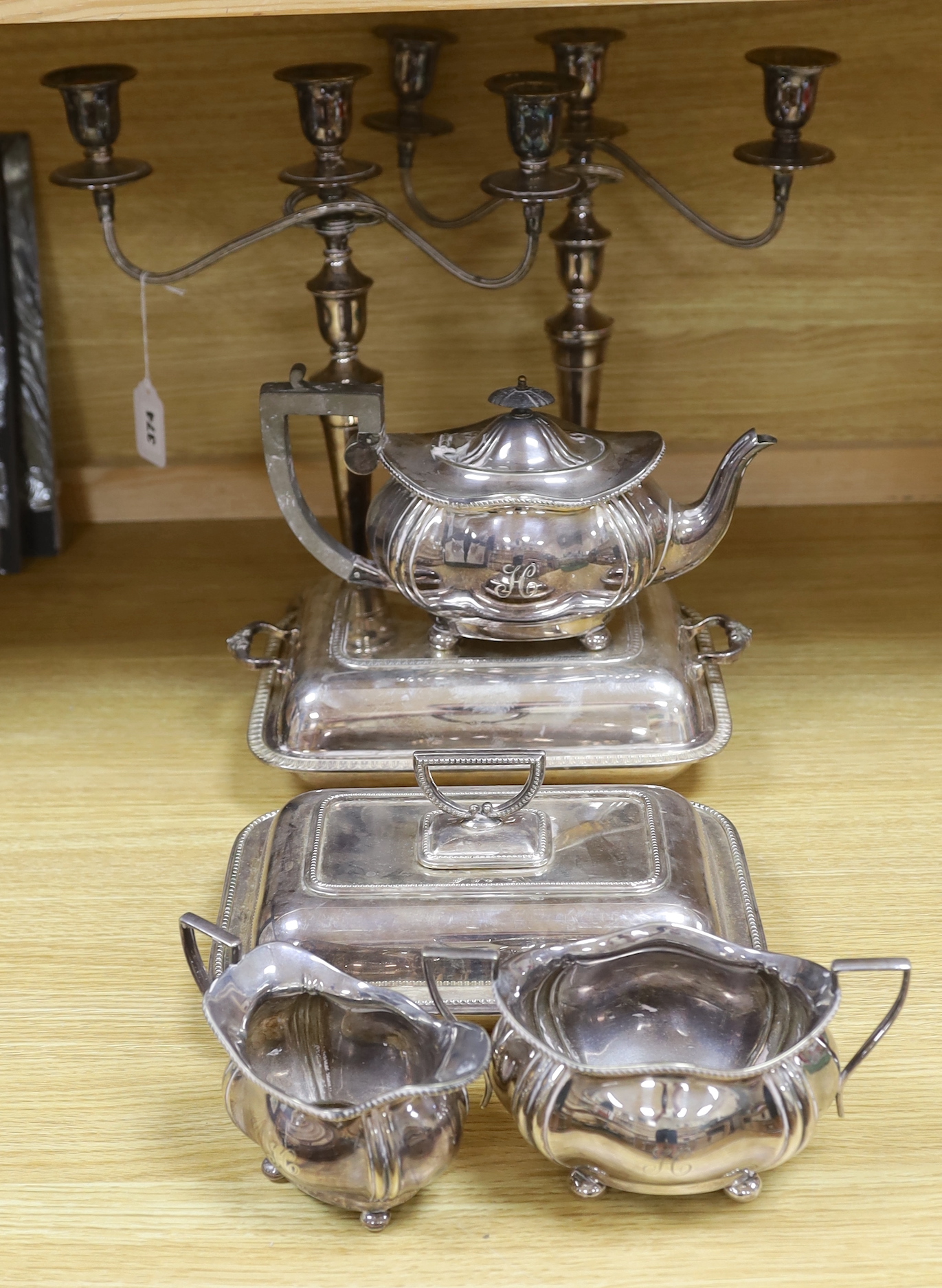 A group of silver plated items including a pair of three branched candlesticks, teapot, milk jug and sugar bowl, the largest 36cm high